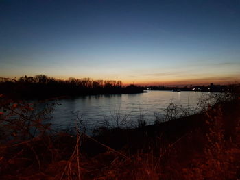 Scenic view of lake against clear sky at sunset