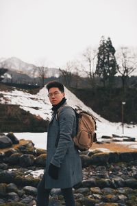 Man standing in snow against sky during winter