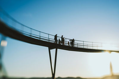 Low angle view of silhouette people on bridge against clear sky