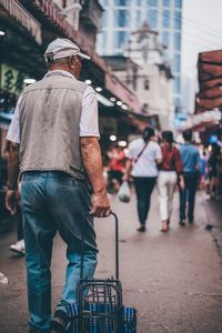 Rear view of man walking on street in city