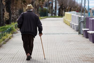Rear view of man walking on footpath