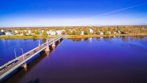 Bridge over river in city against blue sky