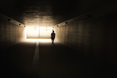 Rear view of man walking in tunnel