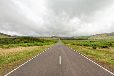 Road passing through land against sky