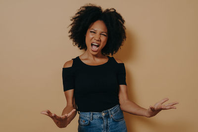 Beautiful young woman standing against orange background