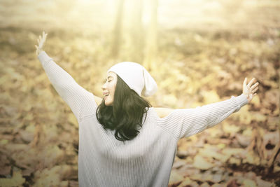 Smiling woman with arms outstretched standing on land during autumn