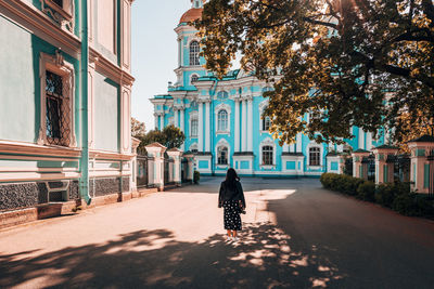 Rear view of woman walking on street amidst buildings