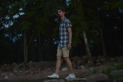 Full length of young man standing on rock in forest