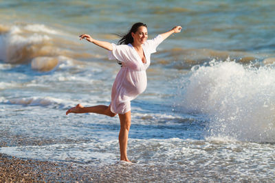 Pregnant woman is jumping on beach. cheerful pregnant woman runs on seashore.