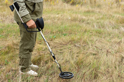 Man with electronic metal detector device working on outdoors.