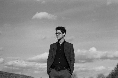 Young man smoking cigarette against sky