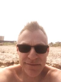 Portrait of young man wearing sunglasses against clear sky