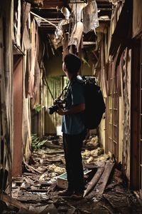 Man holding camera while standing in abandoned building