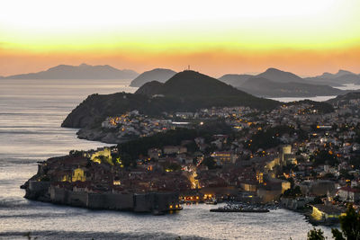 Townscape by sea against sky during sunset