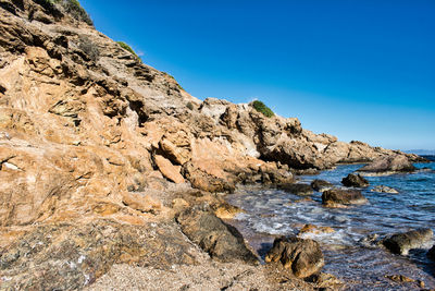 Rock formations in sea against clear blue sky