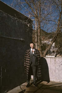 Portrait of young man standing by bare tree