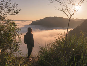 Rear view of woman standing on mountain against sky