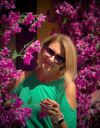 Portrait of young woman wearing sunglasses while standing by plants