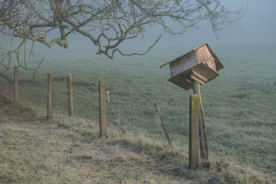 Wooden post on field by trees