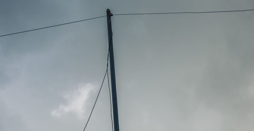 Low angle view of power lines against cloudy sky