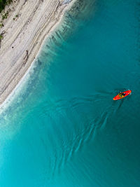 High angle view of person in red boat taken from turquoise sylvensteinstausee bridge on a rainy day