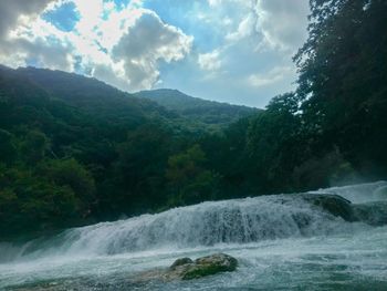 Scenic view of waterfall against sky