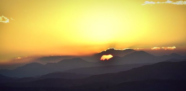 Scenic view of silhouette mountains against romantic sky at sunset