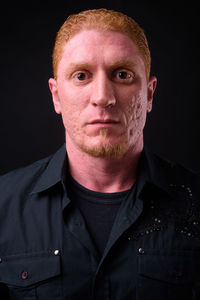 Portrait of young man against black background