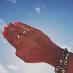 Close-up of woman hand against blue sky