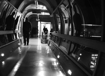 Rear view of people walking in illuminated corridor