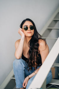 Portrait of beautiful woman sitting against wall