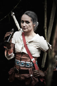 Portrait of young woman wearing costume holding bottle at forest