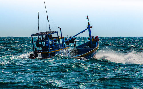 Fishing boat in sea against clear sky