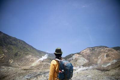 Rear view of man looking at mountain against sky