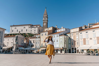 Stylish young woman walking in tartini square in idyllic town of piran, slovenia