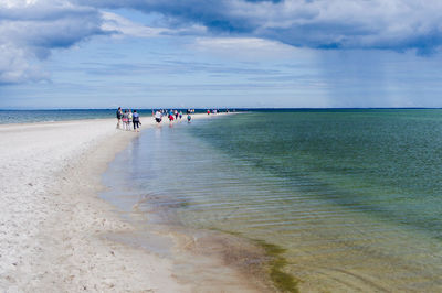 People at beach against sky