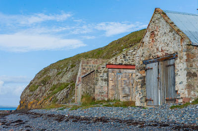 Old house by building against sky