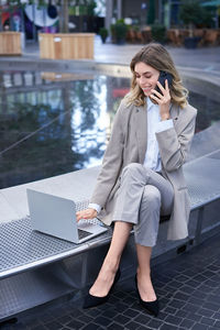 Side view of young woman using phone