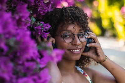 Close-up portrait of a smiling young woman holding purple flower