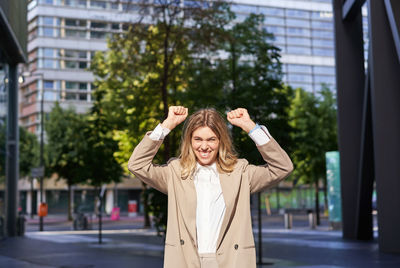 Portrait of young woman standing in city