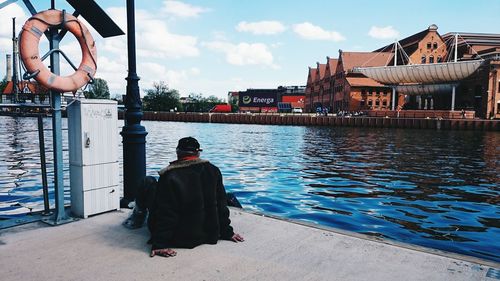 Rear view of woman sitting on riverbank