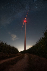 Wind turbines on field against sky at night