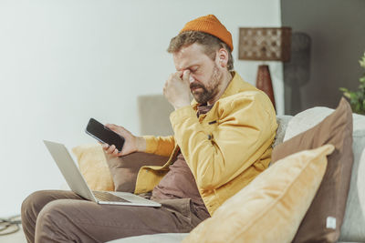 Young man using mobile phone while sitting on sofa at home