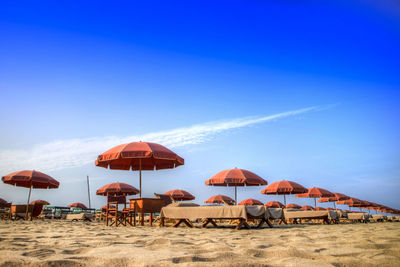 Parasols at beach against blue sky
