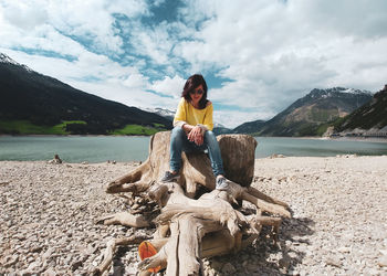 Woman sitting on beach against sky