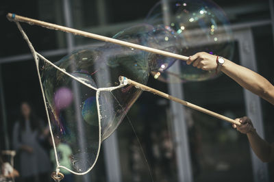 Cropped hands of woman playing with bubbles outdoors