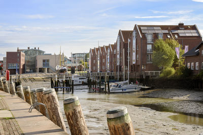 Sailboats moored on river by buildings against sky in city