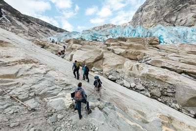 People walking on rocks against mountain range