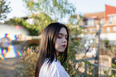 Young woman looking away while standing outdoors