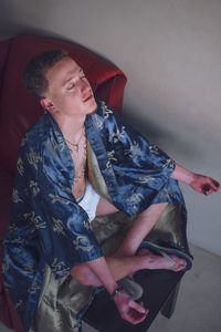 Young man meditating on sofa at home